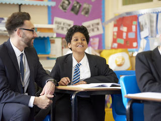 Teacher sits with pupil in class
