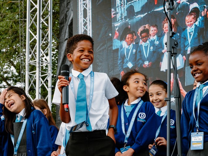 Primary school children laughing as they perform on stage