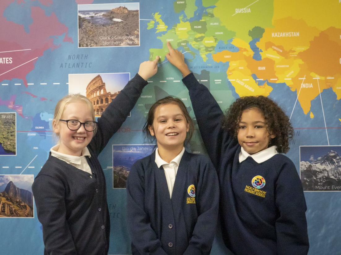 three pupils point to a colourful map
