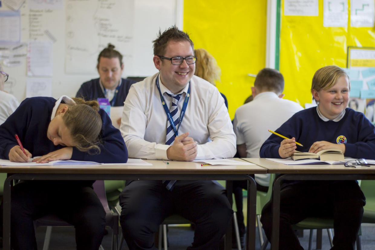 Teacher sitting with pupils in classroom