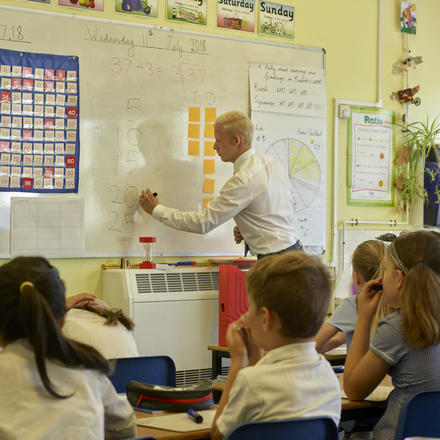 A teacher writes on a whiteboard