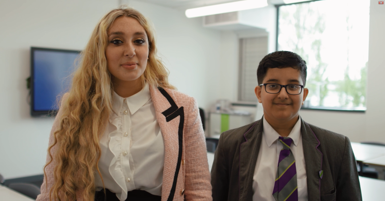 Pupil and teacher standing together in a classroom