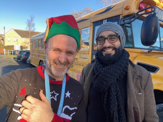 Two males smiling in front of school bus