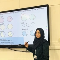 Haleema teaching a maths lesson using a whiteboard.