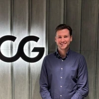Patrick, a Summer Project participant, standing in front of a BCG logo, smiling.
