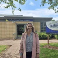 Erica Tilley standing outside Rufford Primary School and Nursery, with the school sign and building in the background.