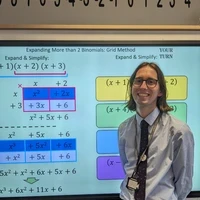 Teacher standing beside a classroom screen displaying lesson content