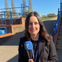 Ellen holding a Teach First microphone outside a school on a sunny day.