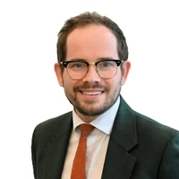 Joshua Fisher, Headteacher at Mercia School, smiling in a suit and glasses.