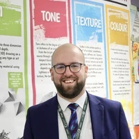 James standing in front of colourful classroom displays.