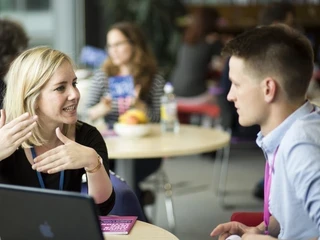 Two young people seating at a table and talking together