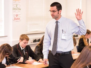 Teacher in class with hand up