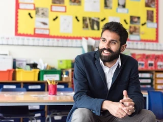 Teacher sitting on desk and smiling
