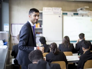 A teacher walks through a classroom observing their pupils.