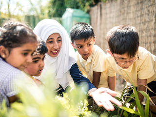 Teacher showing pupils some plants in the school playground.