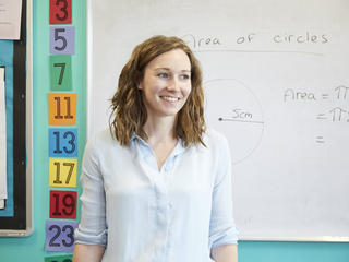 Teacher smiling in front of whiteboard