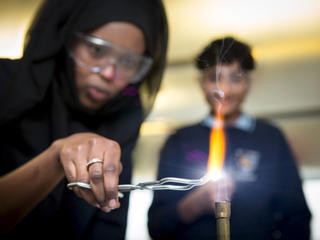 Girl uses bunsen burner in science lesson