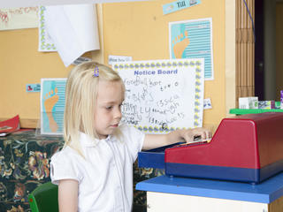 little girl playing with a toy cash register in class