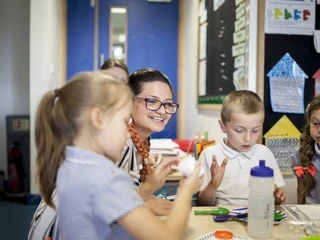 primary school teacher in class helping her pupils