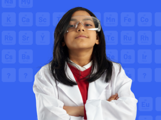 girl in labcoat and science goggles crosses her arms and looks at camera