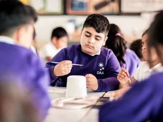 ECF page image boy sitting in classroom, holding a paintbrush