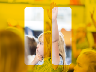 Young girl in primary school class raises her hand