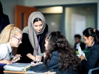 Teacher stood with her students who are working
