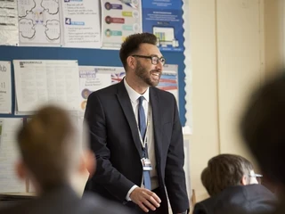 Teacher stood in class smiling