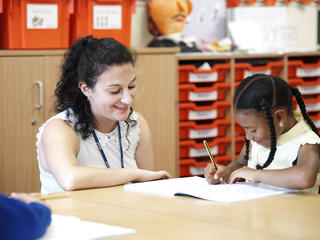 Female teacher and young student smiling and working together