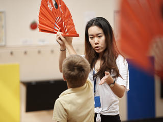 Teacher and student holding a paper fan