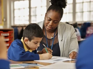 Teacher sat with student at table working