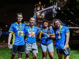 Group of runners wearing Teach First shirts smiling together after a race