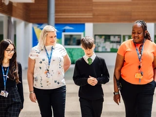 Two school staff members and two pupils walking together through a school.