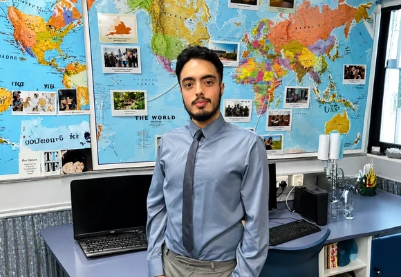 Isaaq standing in a classroom in front of a world map.