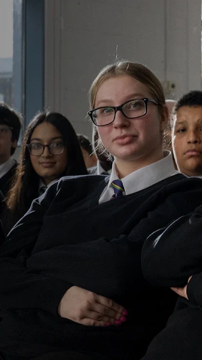 A group of secondary school pupils in uniform sitting together in a classroom.