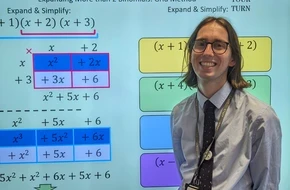 Teacher standing beside a classroom screen displaying lesson content