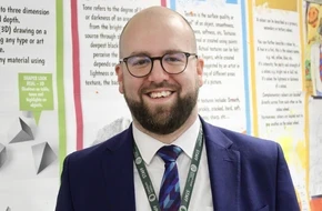 James standing in front of colourful classroom displays.