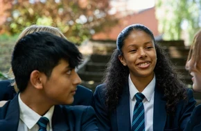 Three students in school uniform talking outside.