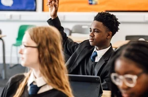 Secondary school pupil raising his hand in class