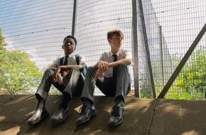 Two secondary school pupils sitting outdoors at school, representing ambition and the opportunities education can create.