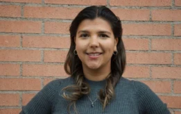 Louise, a Summer Project participant, smiling in front of a brick wall.