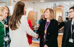 Alison Brannick, Principal of Landau Forte College, speaking with colleagues and students in a school setting.